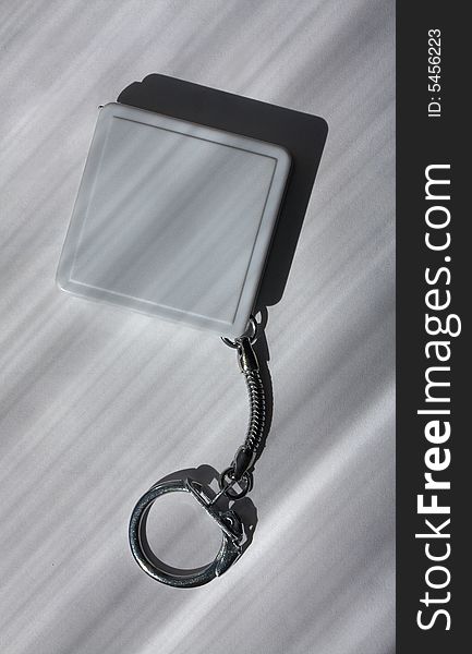 A square plastic charm of grey color on a metal chain with the lock
