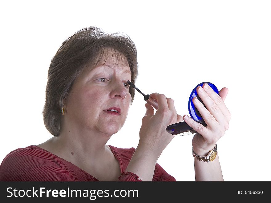 A nice looking woman in red putting on eye makeup. A nice looking woman in red putting on eye makeup