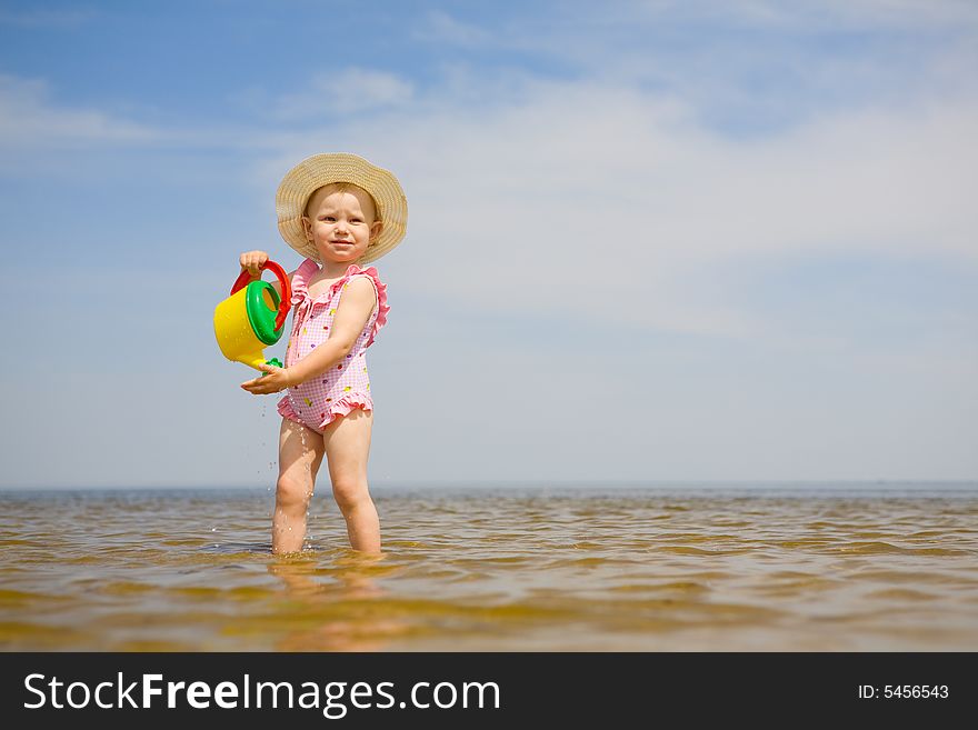 Small girl with watering-pot on the seashore. Small girl with watering-pot on the seashore