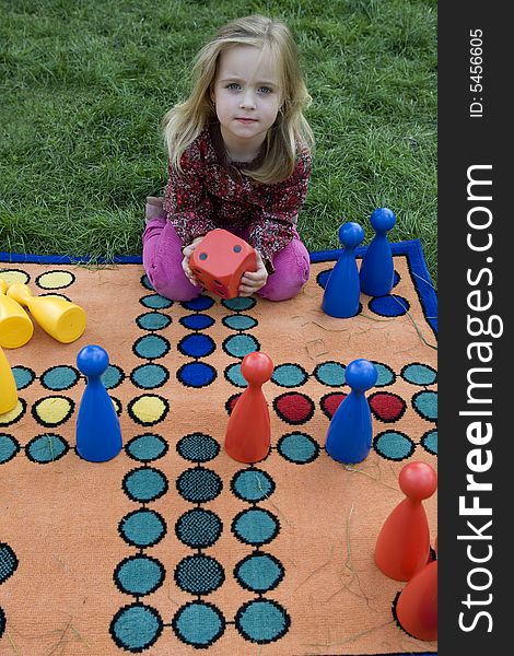 Child playing with a board game on the meadow