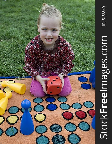 Child playing with a board game on the meadow