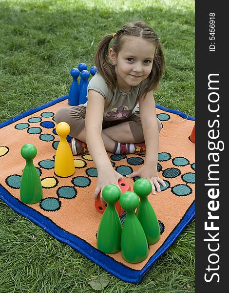 Child playing with a board game on the meadow