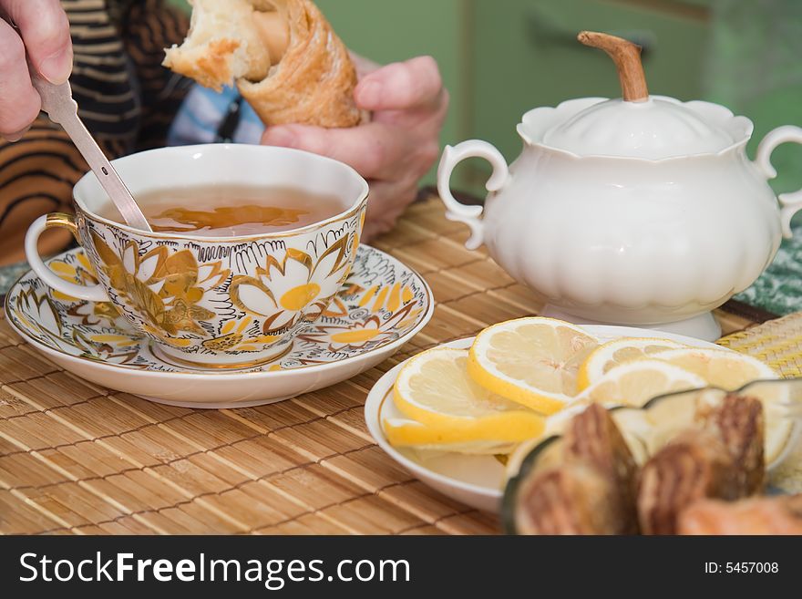 Senior woman drinks tea with sweet rolls