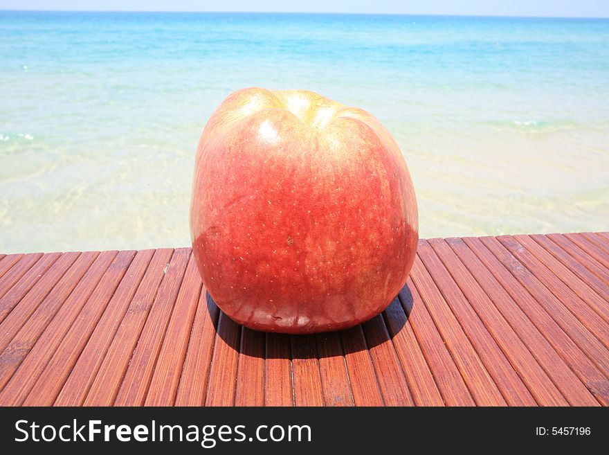 Big red apple on the wood table on the backgraund warm sea