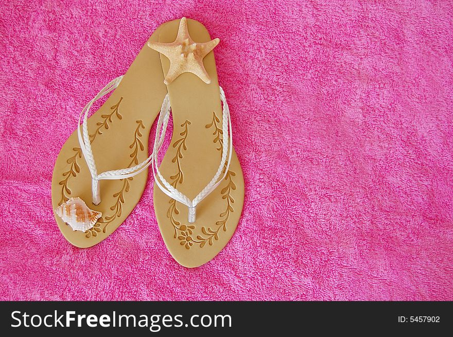 Beach sandals with seashells on pink towel. Beach sandals with seashells on pink towel