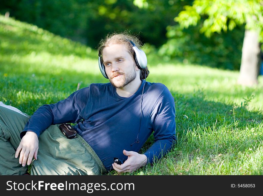 Young man with headphones on the grass. Young man with headphones on the grass