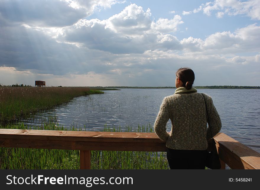 The view of the girl standing by Zuvintas dying lake with bird watching station far away (Lithuania). The view of the girl standing by Zuvintas dying lake with bird watching station far away (Lithuania).