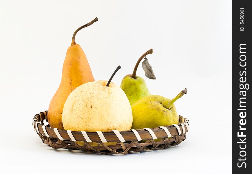 Still life of four types of pears in a wicker basket, namely a Bosc, a Packham, and two Asian pears, a Gong and the fragrant pear.