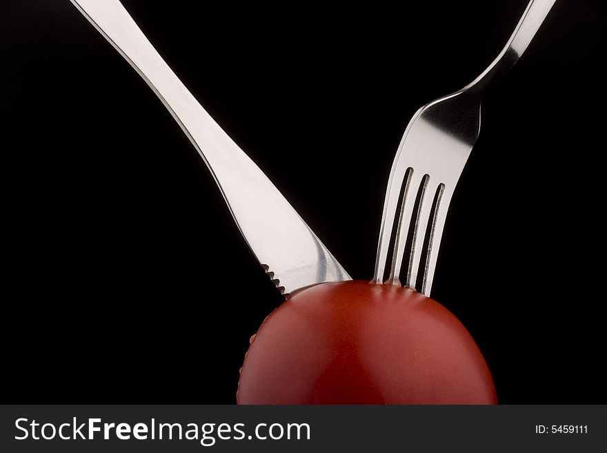 Knife with forks help slices juicy  tomato. Knife with forks help slices juicy  tomato