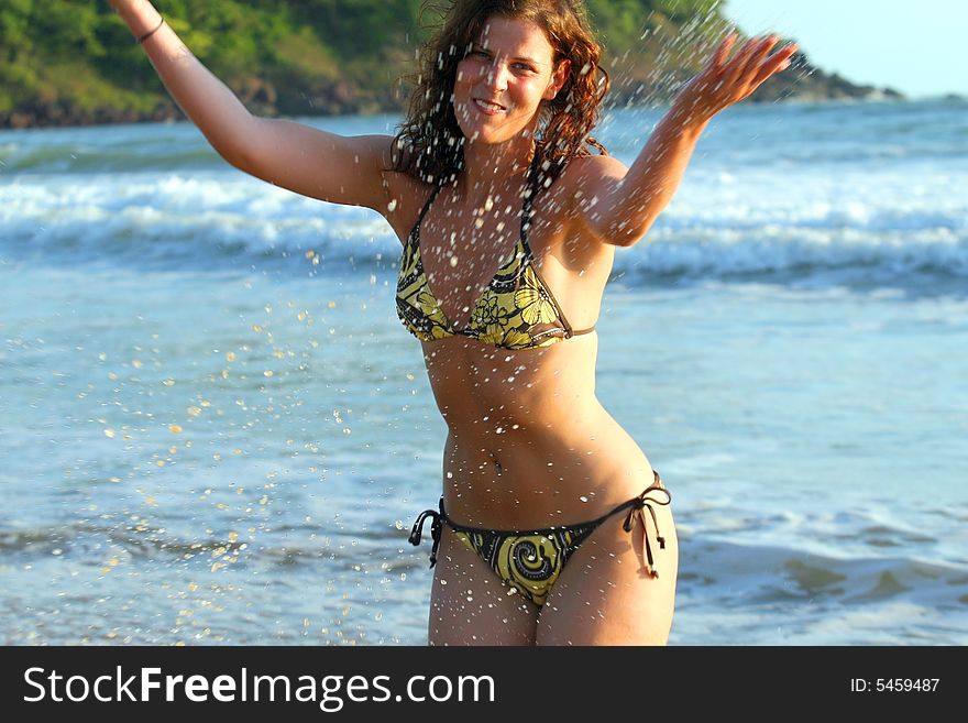 A young woman splashing in the water at the beach. Ideal summer / vacation shot. A young woman splashing in the water at the beach. Ideal summer / vacation shot.