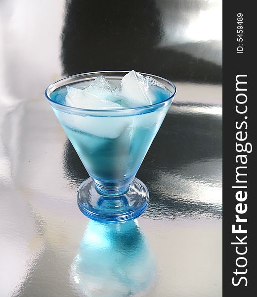 Curacao blue,  licor of orange with blue artificial  color, on a silver background. Curacao blue,  licor of orange with blue artificial  color, on a silver background