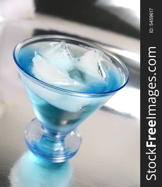 Curacao blue,  licor of orange with blue artificial  color, on a silver background. Curacao blue,  licor of orange with blue artificial  color, on a silver background