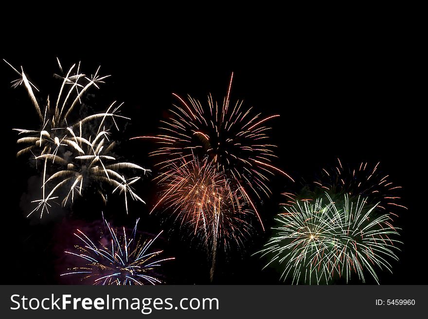 Fireworks display viewed at night. Several different colored fireworks exploding in the sky.