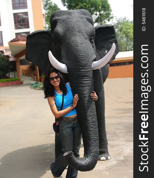 A young sexy Indian Posing with a fake huge elephant kept as a tourist attraction. A young sexy Indian Posing with a fake huge elephant kept as a tourist attraction