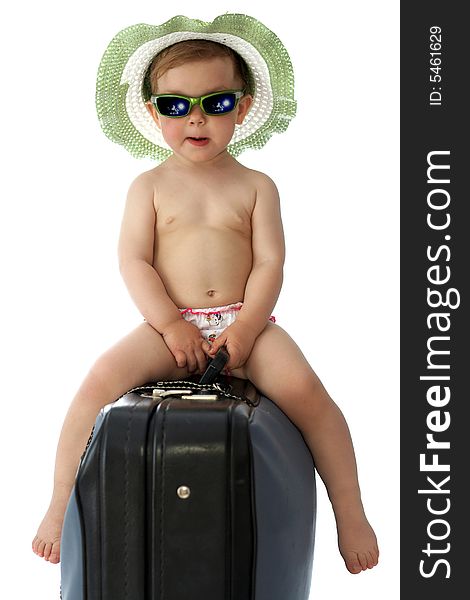 A baby with hat and goggles on a valise. A baby with hat and goggles on a valise