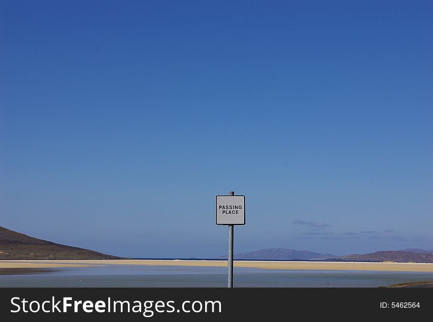 Wide open view of long beach on Uist, Scotland, and a passing place sign