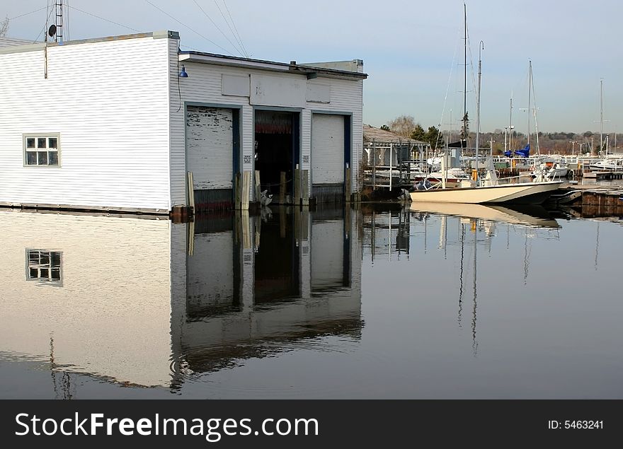 A three bay boathouse reflected in the water at the marina.