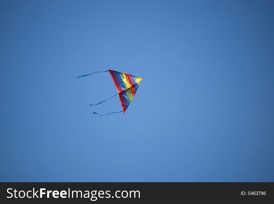 Rainbow kite flying in blue sky