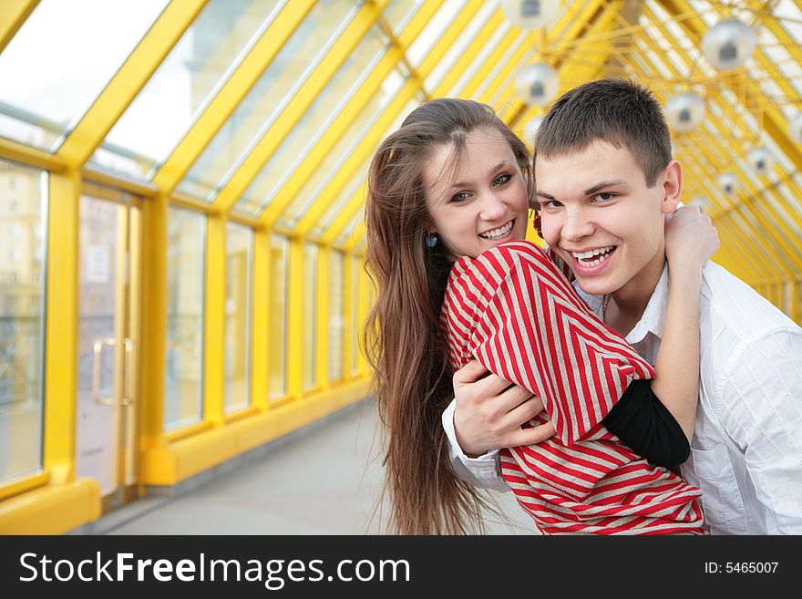 Boy embraces girl on yellow footbridge. Boy embraces girl on yellow footbridge