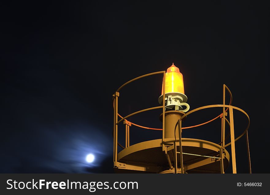 Beacon at night with the moon behind