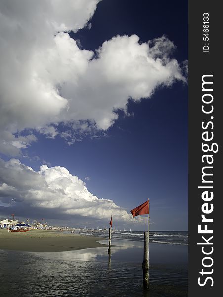 White Cloud In Ablue Sky over a beautiful beach with red security flag in the sea