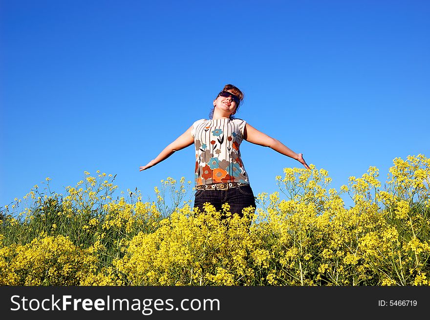 Beautiful girl and yellow flowers over a blue sky. Beautiful girl and yellow flowers over a blue sky