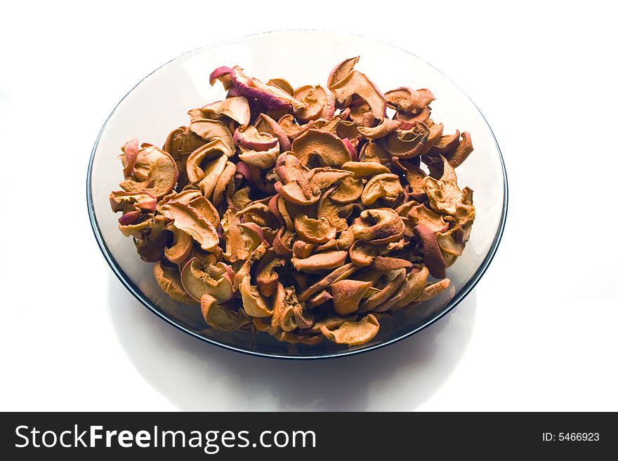 Dry slices of apple on a glass plate on white background