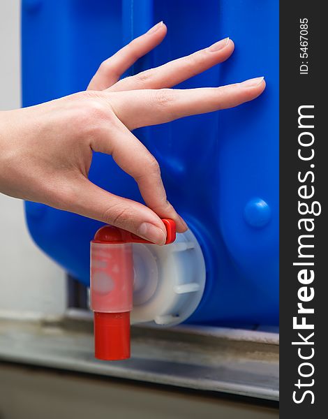 Hand on the red valve of the blue tank; Shallow depth of field. Close-up. Hand on the red valve of the blue tank; Shallow depth of field. Close-up.