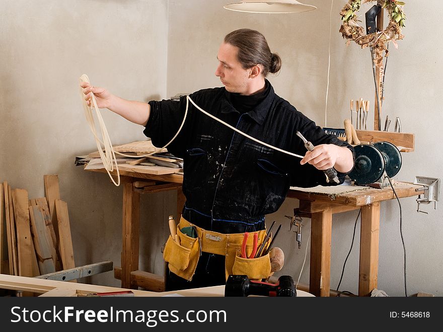 Carpenter	preparing pneumatic chisel in his workshop with hand tools