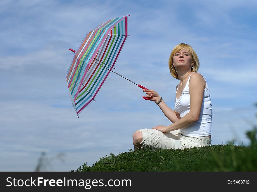 Young charming girl with umbrella against blue sky