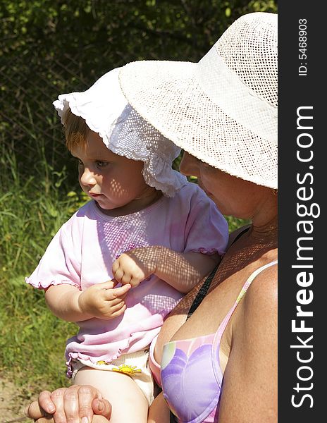 The grand daughter and her grandmother in a straw hat. The grand daughter and her grandmother in a straw hat