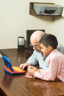Grandfather And Grandson Looking At A Toy Computer Royalty Free Stock Photography Grandfather And Grandson Looking At A Toy Computer Royalty Free Stock Photography