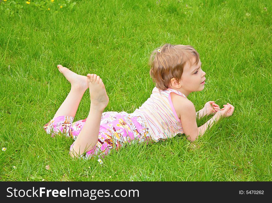 Little girl lies on grass on belly