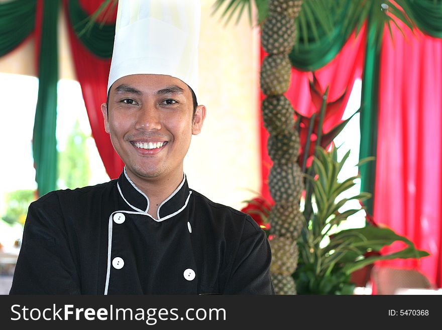 Chef smiling, decorated pineapple at background