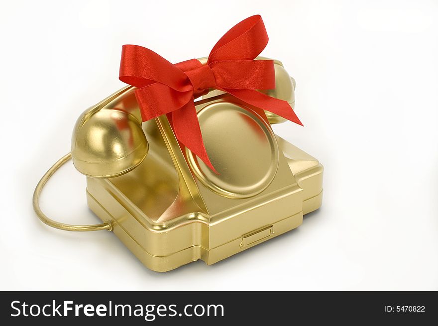 The telephone of gold colour with a red tape on a white background. The telephone of gold colour with a red tape on a white background.