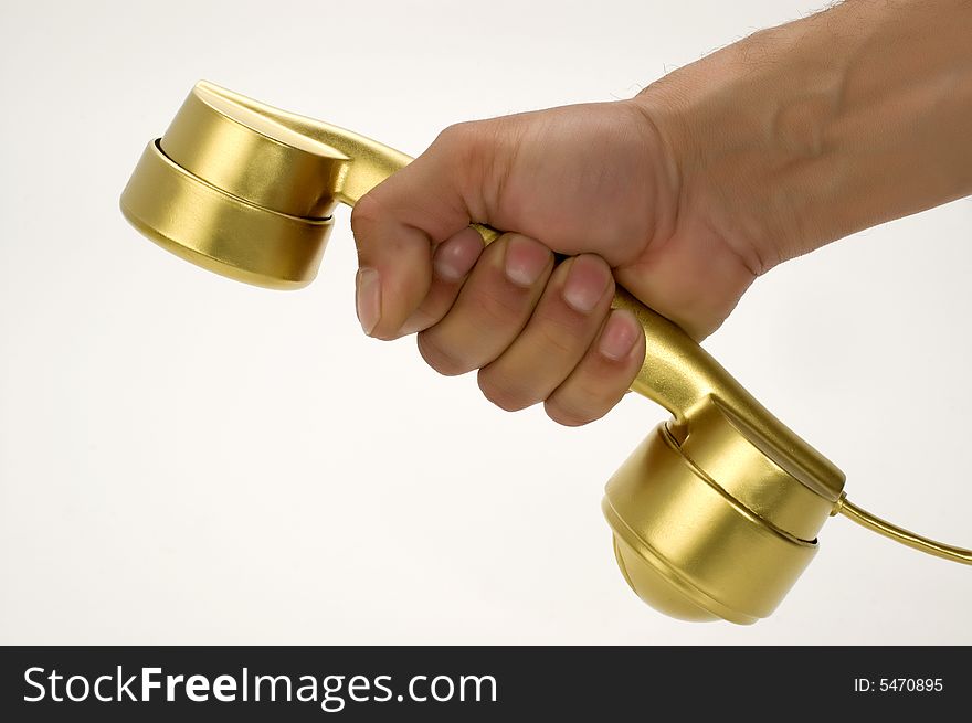 The telephone of gold colour in a hand on a white background. The telephone of gold colour in a hand on a white background.