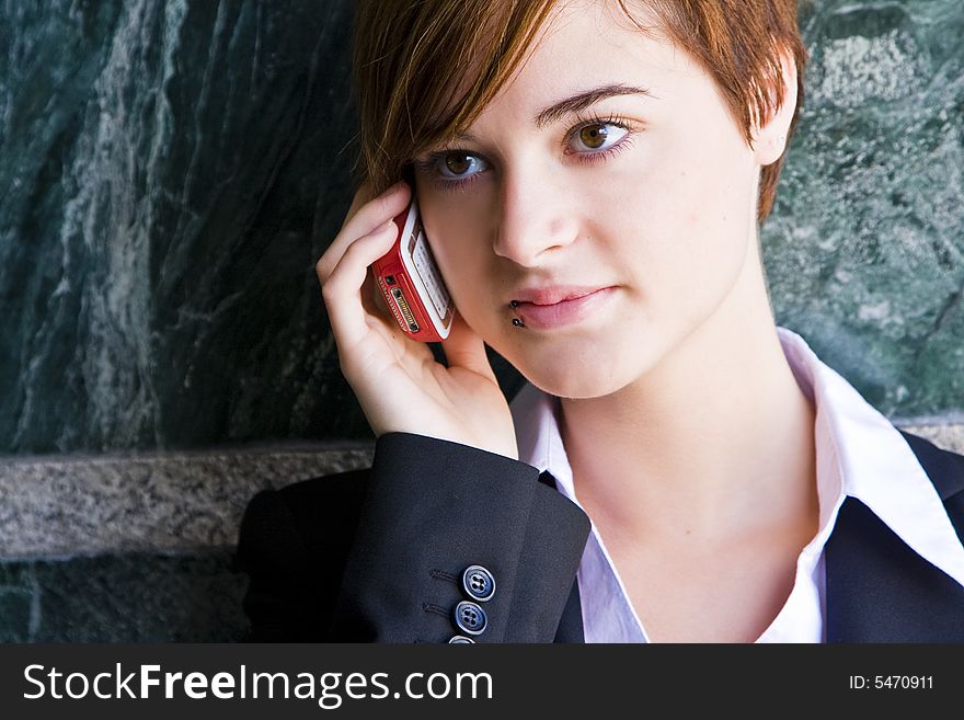 Beautiful businesswoman at phone over marble background.