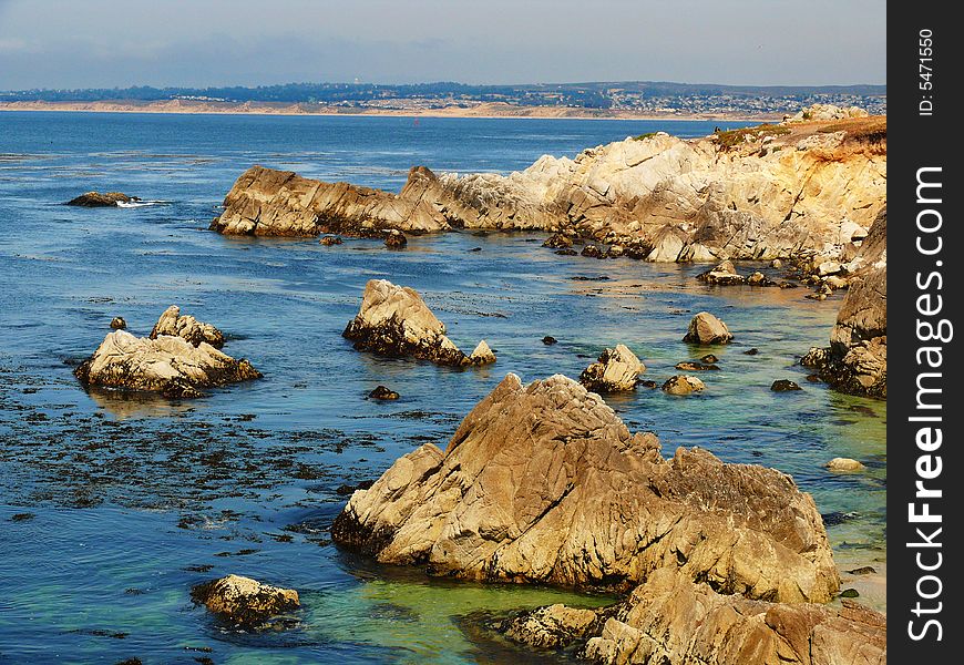 Monterey Bay rugged coastline on a calm day. Blue green ocean kelp and yellow amber rocks. In California near San Francisco. Monterey Bay rugged coastline on a calm day. Blue green ocean kelp and yellow amber rocks. In California near San Francisco.