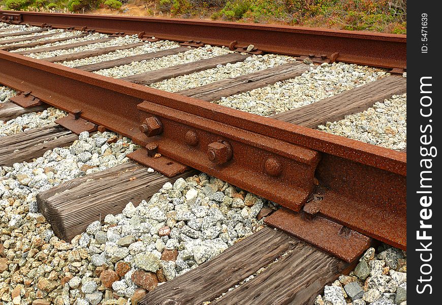 Rusty railroad, unused for a long time, with wooden ties. Crushed stone  track ballast neatly placed between the ties.