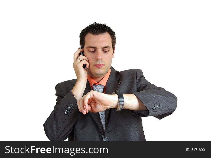 A young businessman, talking over the phone, while looking at his wrist watch. A young businessman, talking over the phone, while looking at his wrist watch