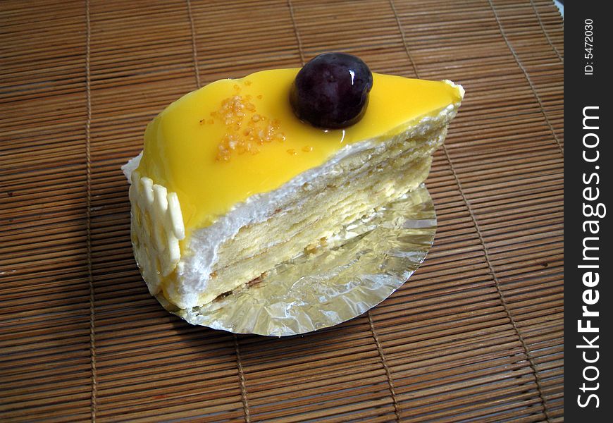 A slide of mango cake with a grape on top