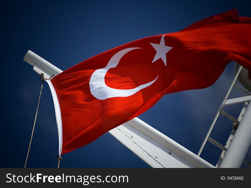 Turkish flag on flagstaff streaming on the wind on the blue sky background

. Turkish flag on flagstaff streaming on the wind on the blue sky background