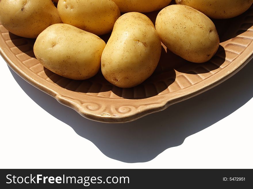 Potato on brown ceramick plate  isolated on white background. Potato on brown ceramick plate  isolated on white background