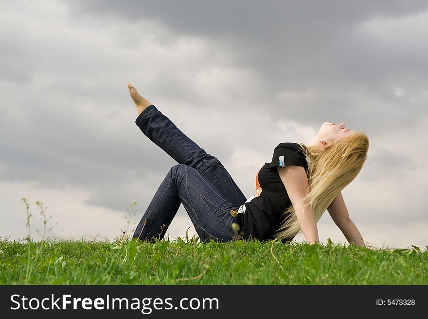 The Young Girl Sitting On A Green Grass