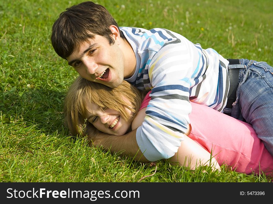 Young Happy Couple Laying On A Green Grass