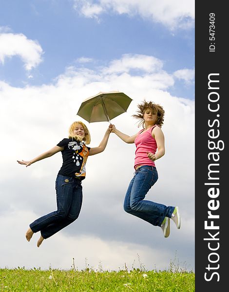 The two happy young girls jumping with a umbrella