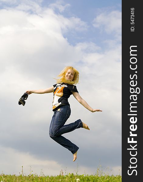 The young happy jumping girl on a background of the blue sky
