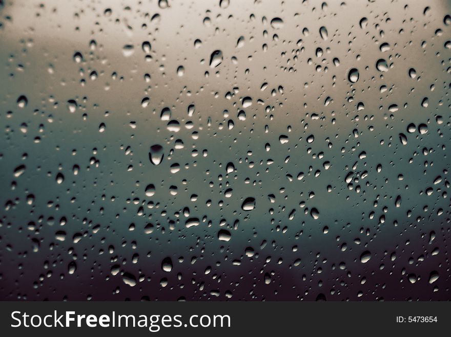 An abstract blend of colours of a window with rain droplets