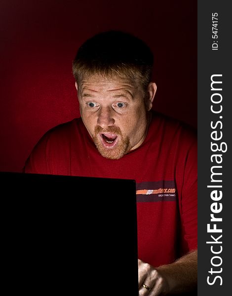 A man looking at a Notebook computer looking astonished. A man looking at a Notebook computer looking astonished