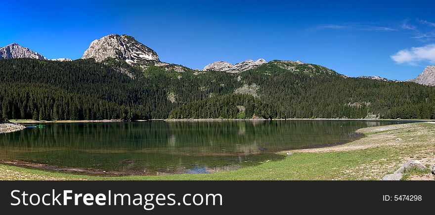 Panorama of mountain lake with evergreen forast around